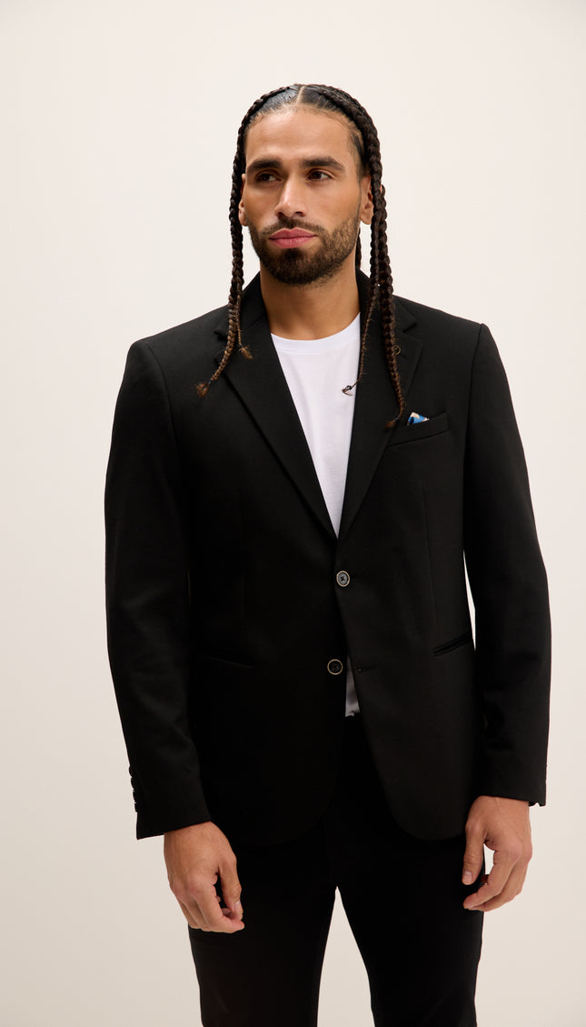Man wearing a black suit with a white shirt on a plain background