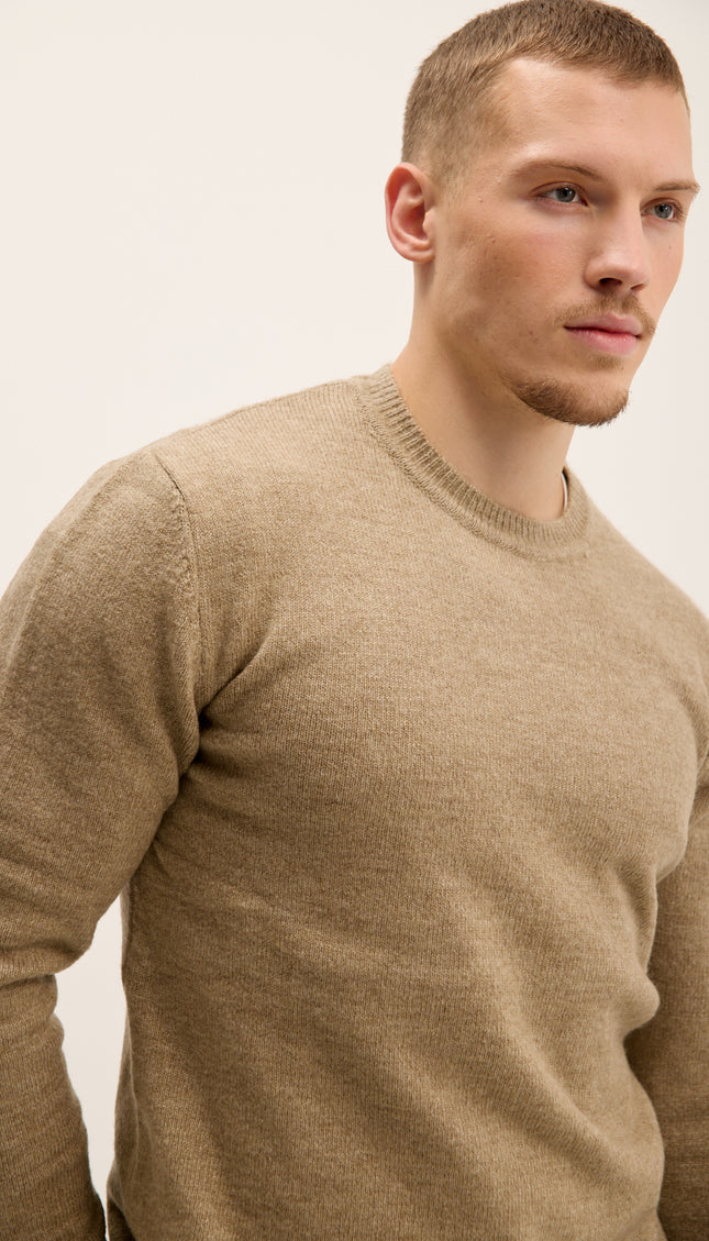 Man wearing a beige sweater against a plain background