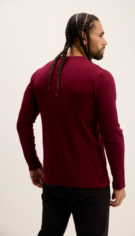 Man wearing a burgundy long-sleeve shirt against a plain background