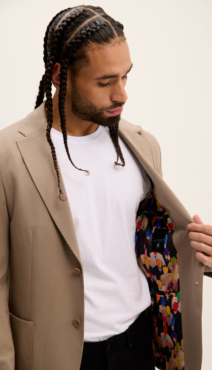 Man wearing a beige blazer over a white shirt with a colorful tie, on a plain background