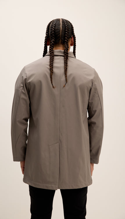 Person wearing a beige coat from behind on a plain background