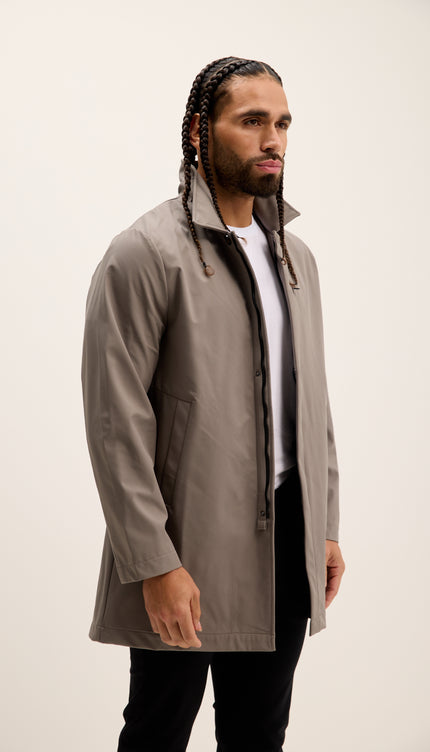Man wearing a beige raincoat against a plain background