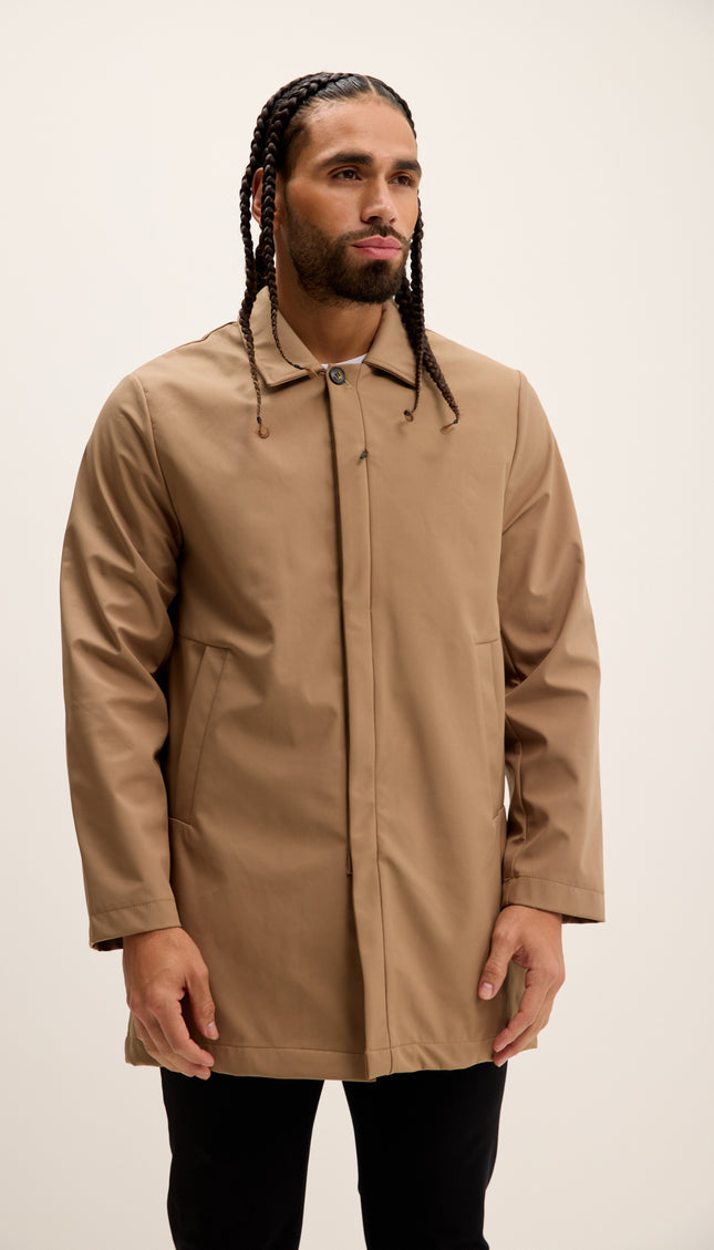 Man wearing a beige raincoat against a plain background