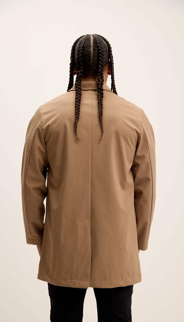 Person wearing a beige coat from behind on a plain background