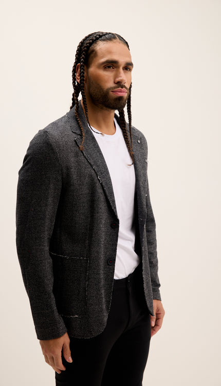 Man wearing a gray blazer over a white shirt on a plain background