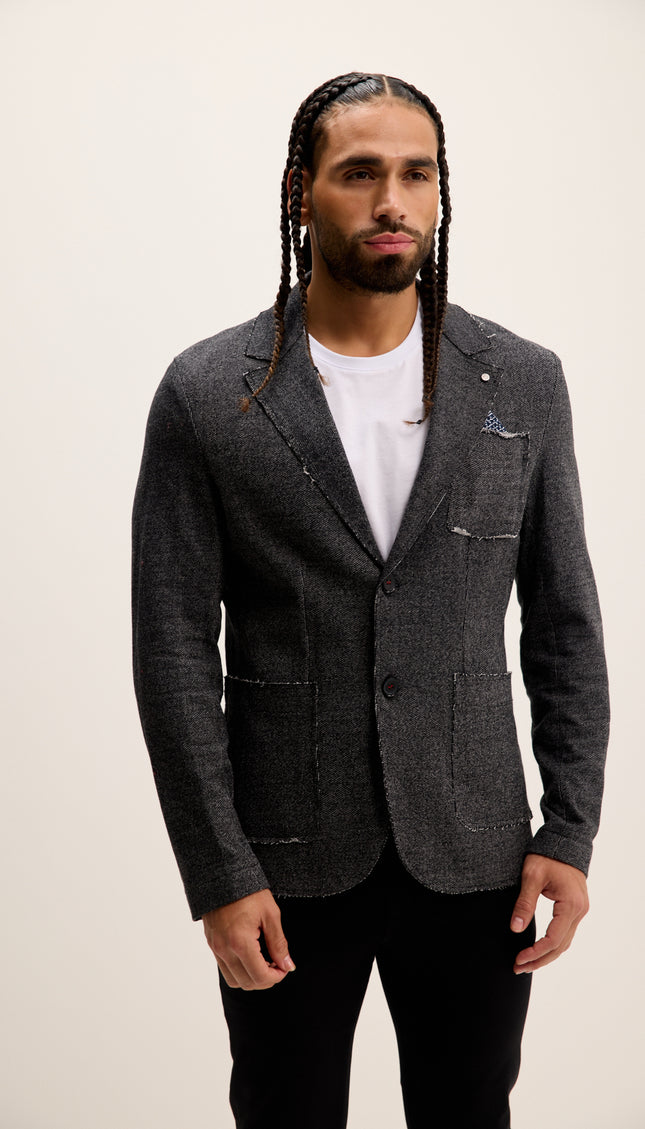 Man wearing a gray blazer over a white shirt with a plain background