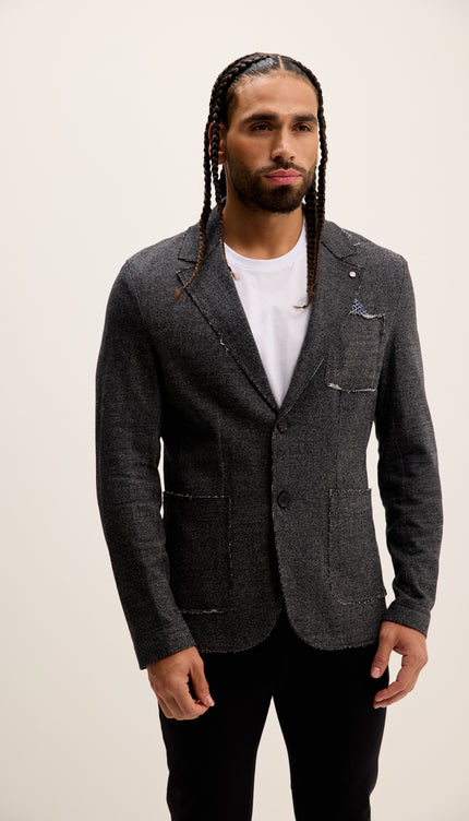 Man wearing a gray blazer over a white shirt with a plain background