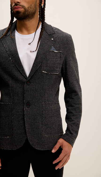 Man wearing a dark gray blazer over a white shirt with a neutral background