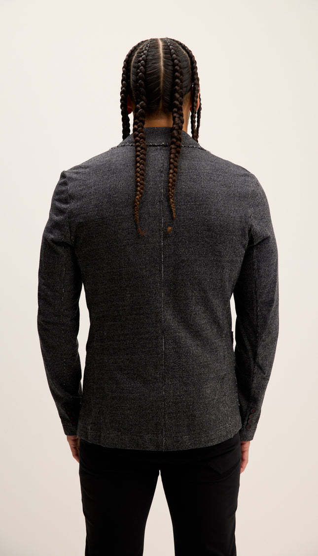 Person wearing a dark gray blazer from behind on a plain background