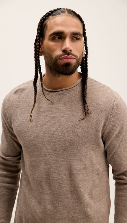 Man with braided hair wearing a brown sweater against a plain background