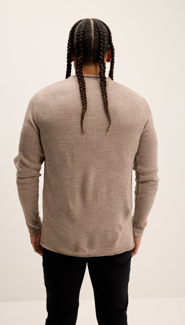 Person wearing a beige sweater and black pants with braided hair on a white background