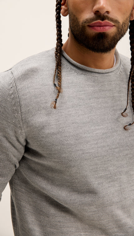 Man wearing a gray long-sleeve shirt with braided hair against a neutral background