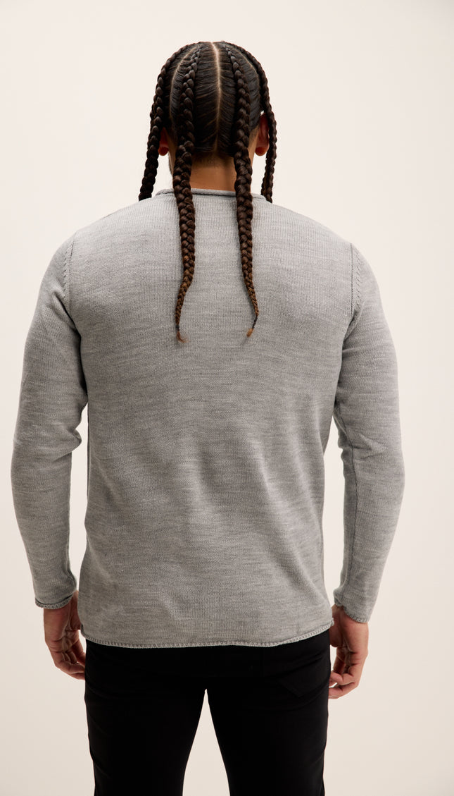 Person wearing a gray long-sleeve shirt with braided hair on a plain background