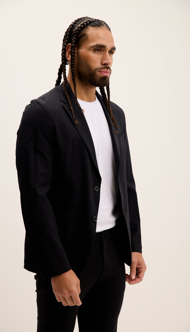 Man wearing a black suit and white shirt against a plain background