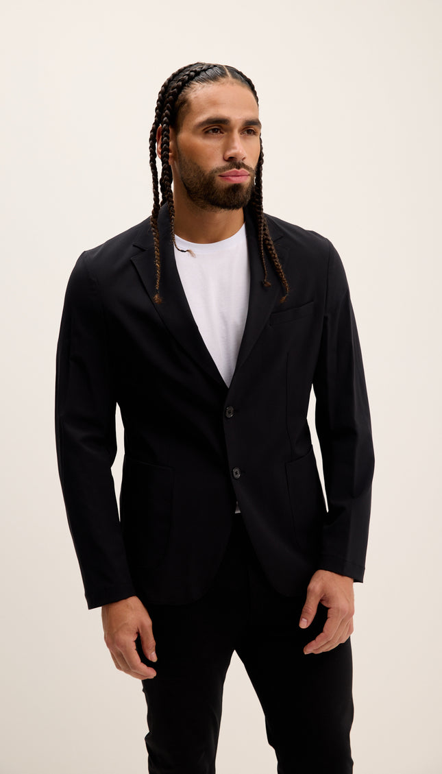 Man wearing a black blazer over a white shirt on a beige background