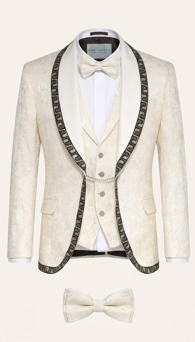 Cream floral brocade shawl lapel tuxedo suit with intricate decorative trim, matching vest, and bow tie for mens formal wear.