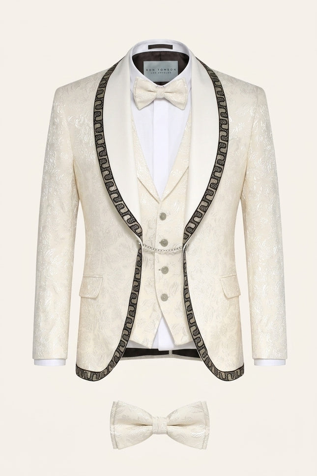 Cream floral brocade shawl lapel tuxedo suit with intricate decorative trim, matching vest, and bow tie for mens formal wear.